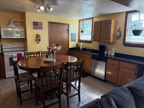 Una cocina con armarios de madera, un lavavajillas de acero inoxidable y una mesa de comedor con sillas.