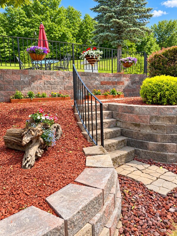 A landscaped garden area with a stone staircase, mulch, and flower planters.