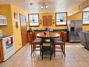 A kitchen with a round wooden table, chairs, a refrigerator, and a microwave.