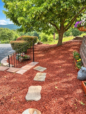 A landscaped garden pathway with stepping stones, a small hedge, and a statue.
