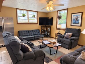 A living room with a sectional sofa, a coffee table, a television, and a ceiling fan.