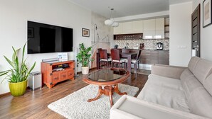 A modern living room with a flat-screen TV, a round glass coffee table, and a beige sofa. - Lion Apartments - Parkur 2 (Sopot)