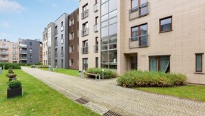 A modern apartment building with a paved walkway, green lawns, and a well-maintained garden area. - Lion Apartments - Parkur 2 (Sopot)