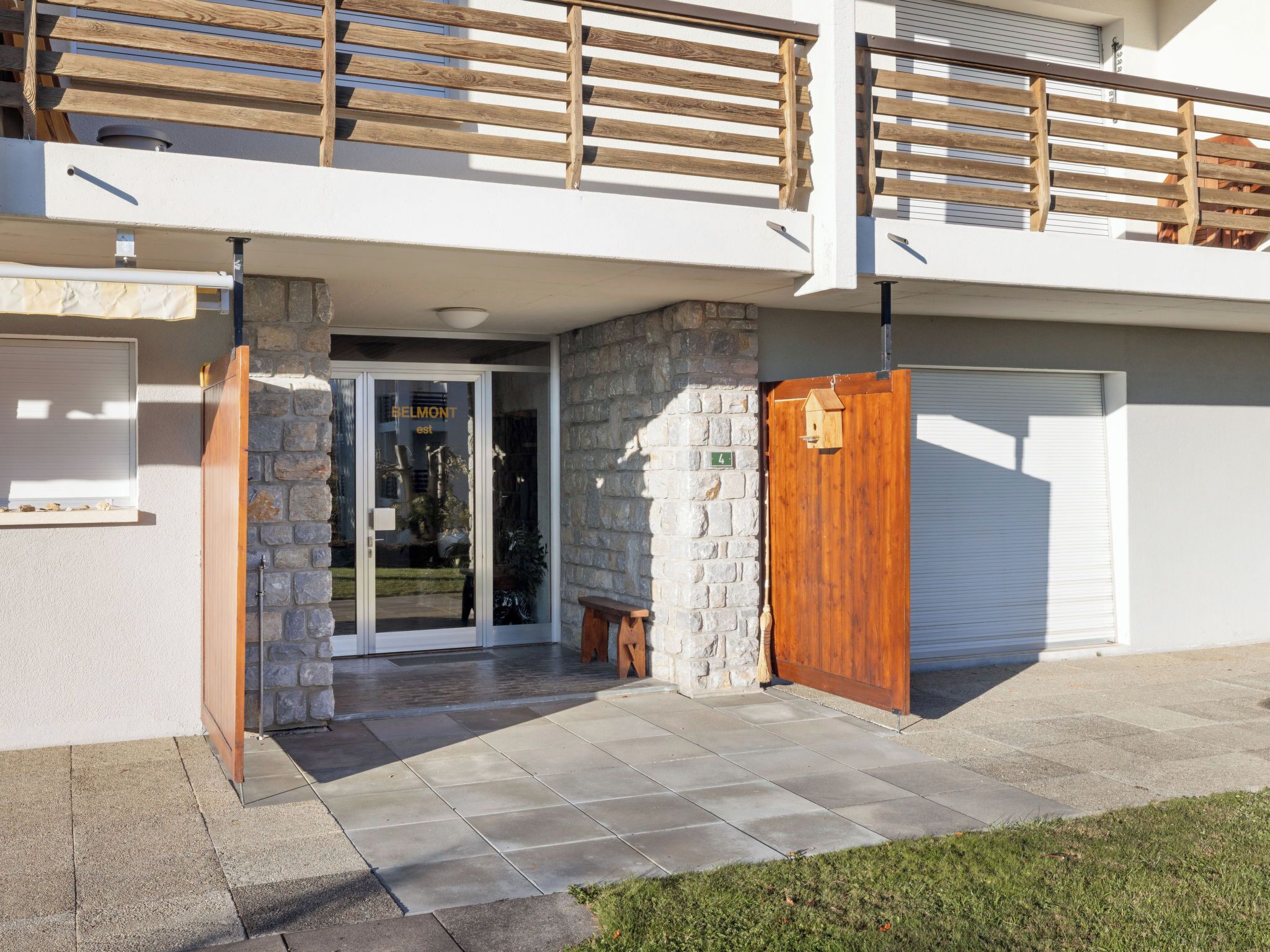 Un bâtiment moderne à deux étages, doté d’une façade en pierre, d’un portail en bois et d’une porte de garage.