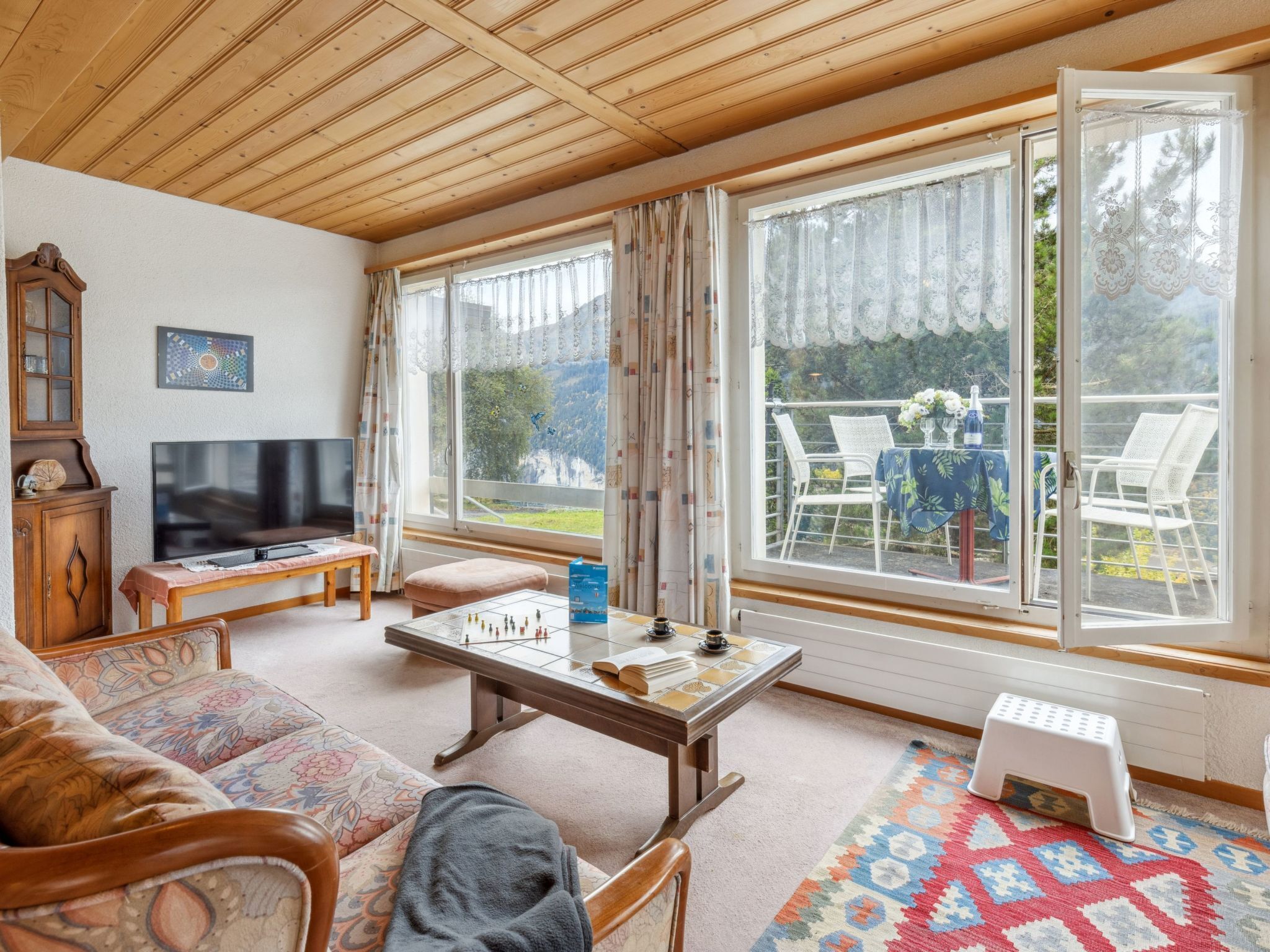 Ein gemütliches Wohnzimmer mit Holzboden, einem Fernseher, einem Schachbrett und einem Sofa.