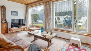 A cozy living room with a wooden ceiling, a television, a chessboard, and a sofa. - Bristol Apt.A by Interhome (Wengen)