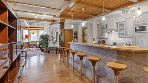 A spacious kitchen with wooden bar stools, a central island, and a view into the dining area. - Bristol Apt.A by Interhome (Wengen)