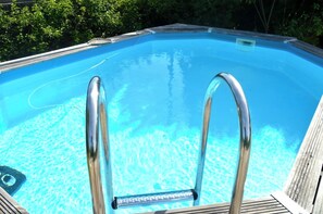 A swimming pool with clear blue water, metal ladder, and wooden deck. - 🥭Mango An Nou: A bungalow with a pool, nature, and beaches (Le Moule)