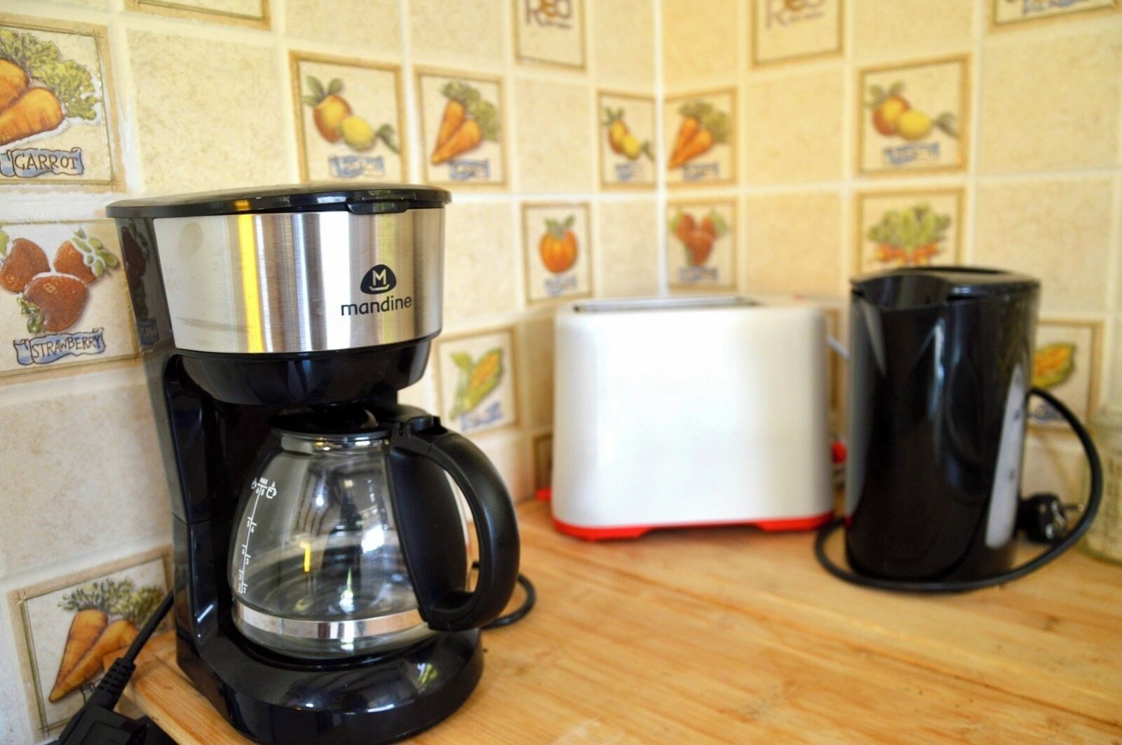 A coffee maker on a kitchen counter with a toaster and a mug in the background.