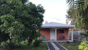A house with a gravel driveway leading to a door, surrounded by greenery and a small garden. - 🥭Mango An Nou: A bungalow with a pool, nature, and beaches (Le Moule)