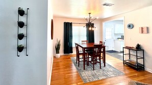 A dining area with a wooden table and chairs, a potted plant, and a hanging light fixture. - Modern 2-bedroom 1930's Bungalow Close to Downtown (Midland)