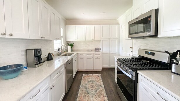 A modern kitchen with white cabinetry, a stainless steel stove, a microwave, and a coffee maker. - Modern 2-bedroom 1930's Bungalow Close to Downtown (Midland)