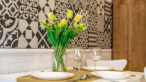 Une table à manger dressée avec de l’assiette blanche, des couverts en argent et un vase rempli de tulipes jaunes.