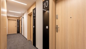 Un corridoio con pavimenti rivestiti di moquette, pareti in legno e porte numerate che conducono alle stanze.
