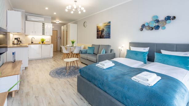 Una camera d'albergo moderna con un letto grande, un divano, un angolo ristoro e angolo cottura.