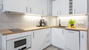 Una cucina moderna con mobili bianchi, forno integrato, macchina del caffè e lavello.