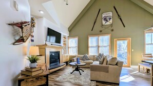 A spacious living room with a fireplace, a television, and a large window. - Stunning/Walk to Summer Festivals/Hot Tubs (Keystone)