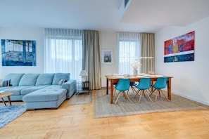 Uma sala de estar moderna com um sofá seccional, uma mesa de jantar com cadeiras e obras de arte nas paredes.