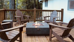 Une terrasse avec quatre fauteuils Adirondack et un foyer carré.