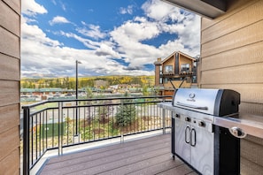 Un balcon doté d’une grille en acier inoxydable, une vue sur une ville et, au loin, un bâtiment en bois.
