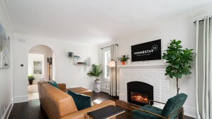 Een moderne woonkamer met een open haard, leren bank en een groene fauteuil.