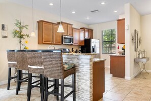 A modern kitchen with wooden cabinets, a central island, and bar stools. - Comfortable 5 bed 4.5 bath home that sleeps 10 (Davenport)
