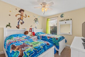 A child's bedroom with two beds, a ceiling fan, a window with curtains, and a wall-mounted TV. - Comfortable 5 bed 4.5 bath home that sleeps 10 (Davenport)