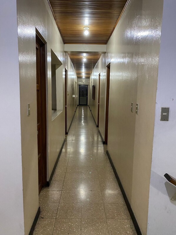 A long, narrow hallway with tiled flooring and wooden doors on both sides.