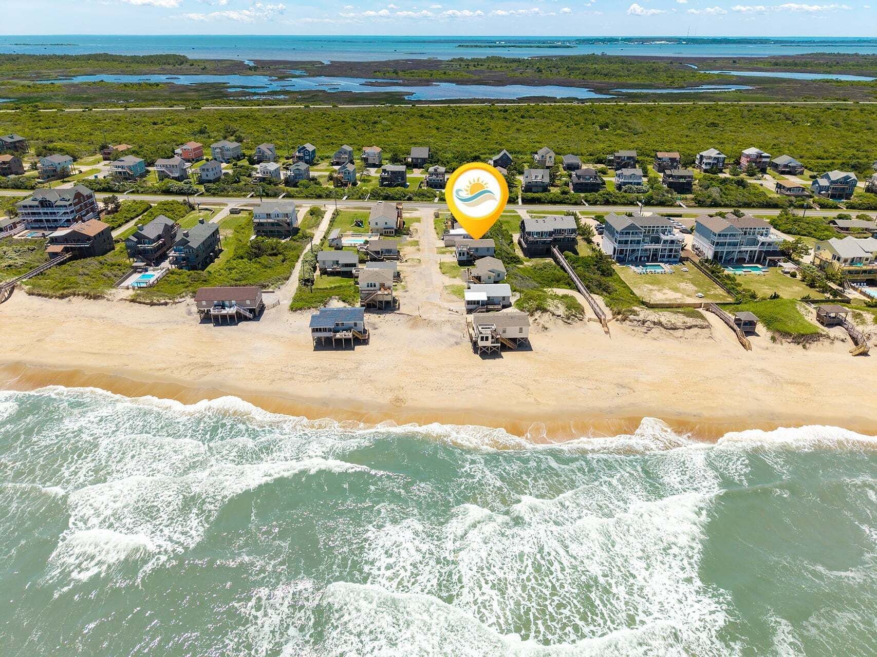 Vista aerea di una zona residenziale costiera con case, una spiaggia e un corpo d'acqua.