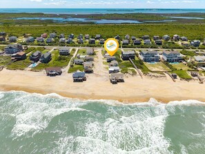 Vista aérea de uma área residencial costeira com casas, uma praia e um corpo de água.