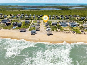 Vista aérea de uma área residencial costeira com casas, uma praia e um corpo de água.