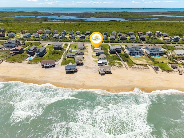 An aerial view of a coastal residential area with houses, a beach, and a body of water.