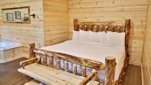 A wooden cabin room with a bed, a bench, and a small shelf with decorative items.