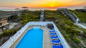 A pool area with lounge chairs, a wooden deck, and a sunset view. - Just Fab * Oceanfront * Elevator * Saltwater Pool * Hot Tub * Game Room * Views (Nags Head)