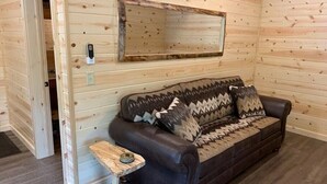 Ein Holzinnenraum mit einer Couch, einem kleinen Tisch und einem Spiegel an der Wand.