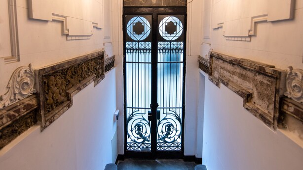 Una imponent escala que condueix a una porta amb un panell de vidre decoratiu i un penjador de cristall.