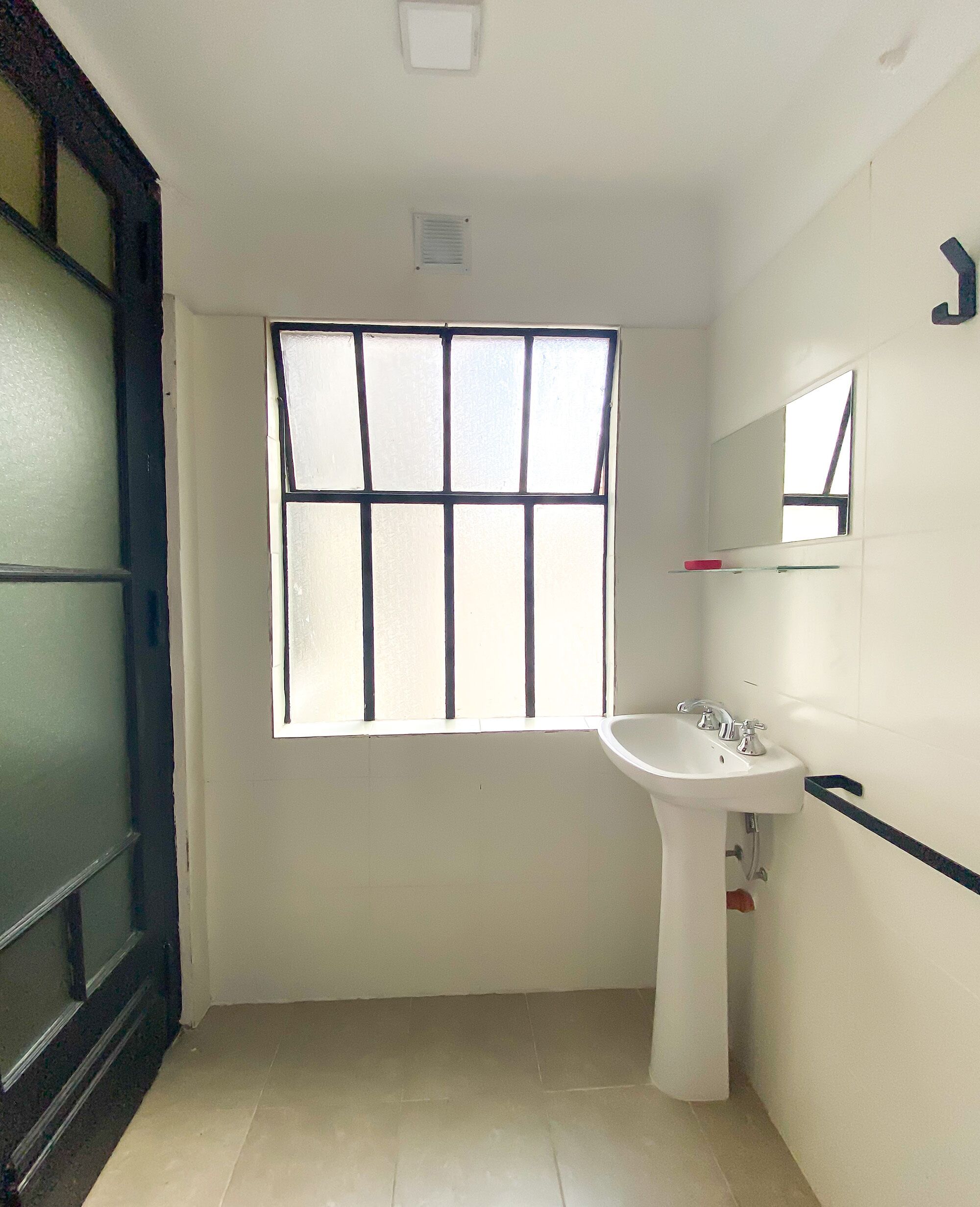 A bathroom with a window, a sink, and a mirror.