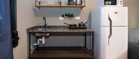 A compact kitchen with a sink, stove, and a white refrigerator.