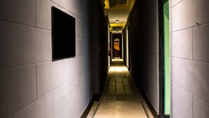 Un passadís estret amb parets i terra de rajola, que condueix a una porta al final.