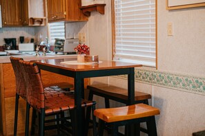 Enjoy meals in this cozy kitchen with a wooden table and chairs, a coffee maker, and a window with blinds.