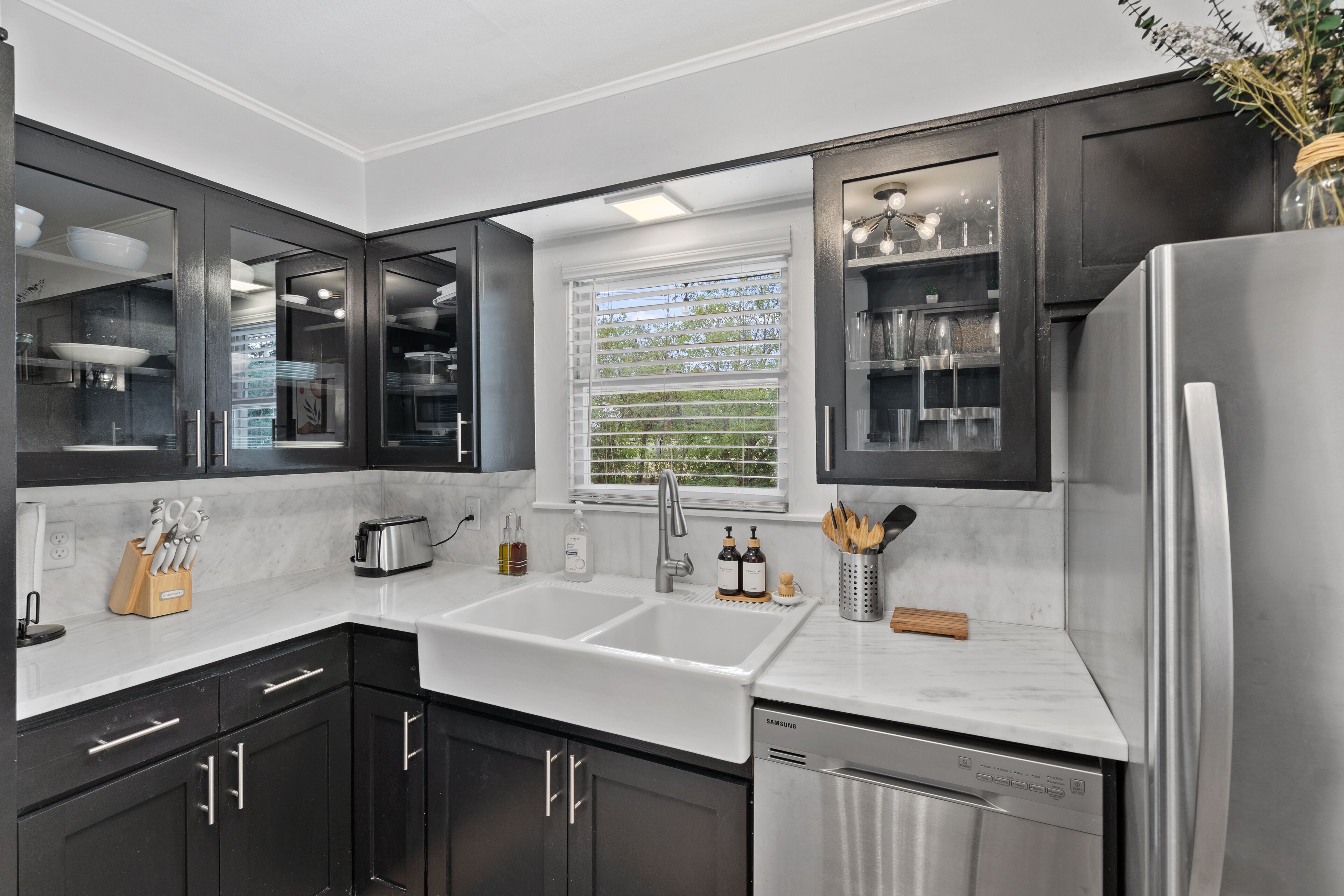 A modern kitchen with dark cabinets, a double sink, and stainless steel appliances.