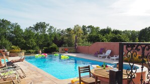 Ein Poolbereich mit Liegestühlen, einem Tisch und aufblasbaren Spielzeugen.