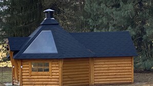 Eine Holzhütte mit geneigtem Dach und Schornstein.