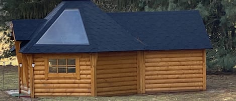 A wooden log cabin with a sloped roof and a chimney.