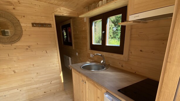 Eine kleine Küche mit Holzausstattung, Spüle und Kühlschrank.