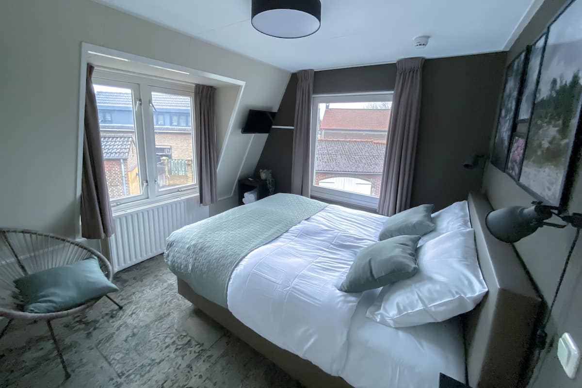 Une chambre à coucher avec un lit, une chaise, une fenêtre et un luminaire au plafond.