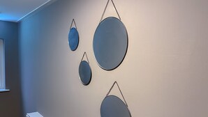 Een muur met drie ronde spiegels in verschillende formaten, elk aan een ketting.