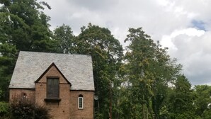 Ein rustikales Backsteinhaus mit geneigtem Dach und einer kleinen Veranda.