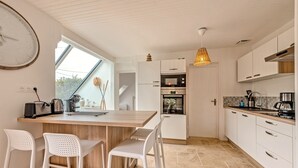 Una cocina moderna con armarios blancos, una isla de madera y una lámpara colgante.