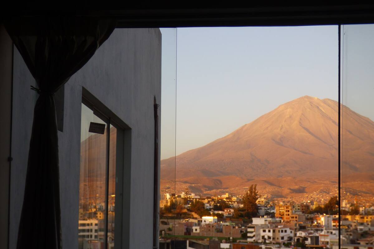 A view of a cityscape with a mountain in the background through a window.